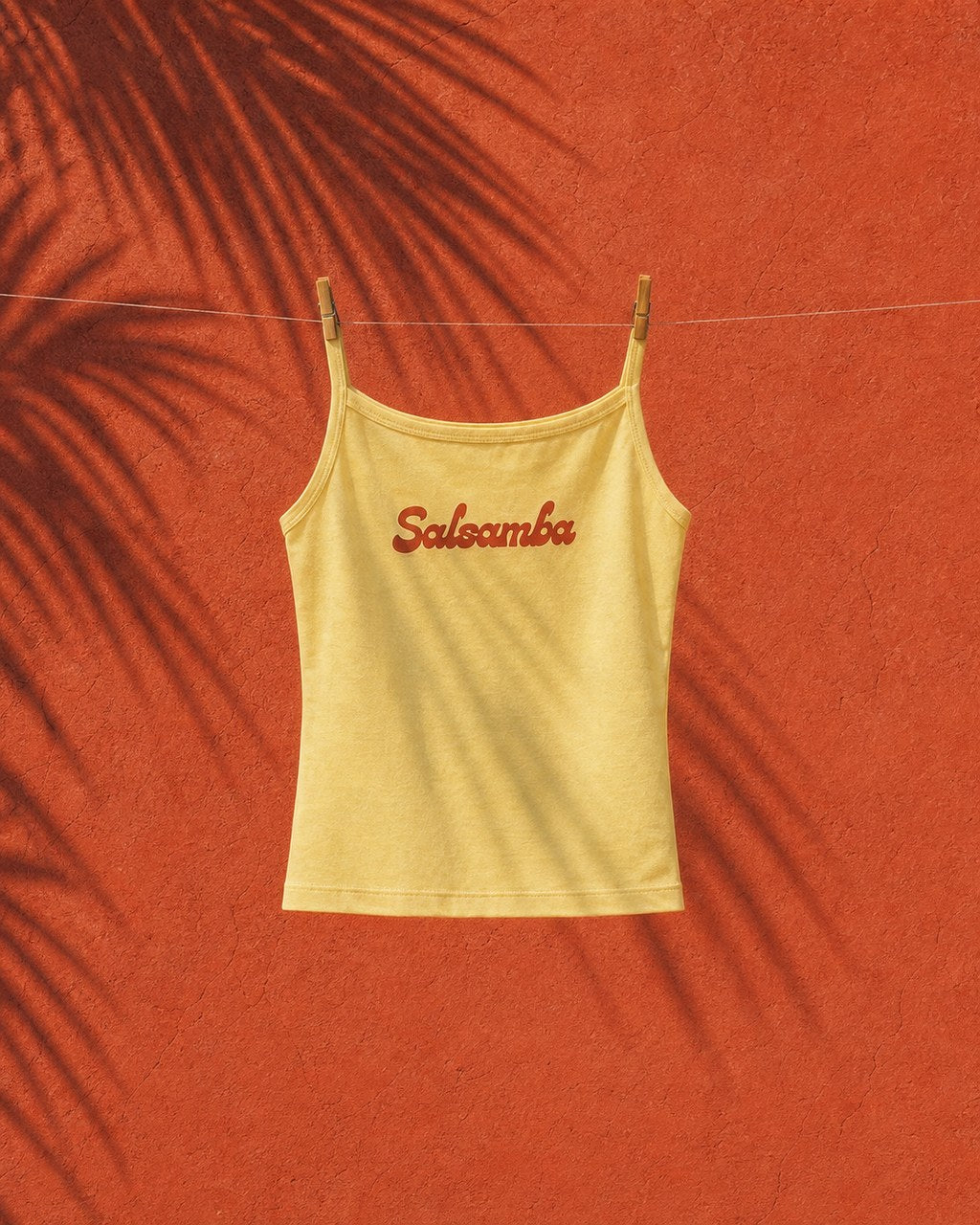 Baby yellow Salsamba tank on a clothesline against terracotta plaster
